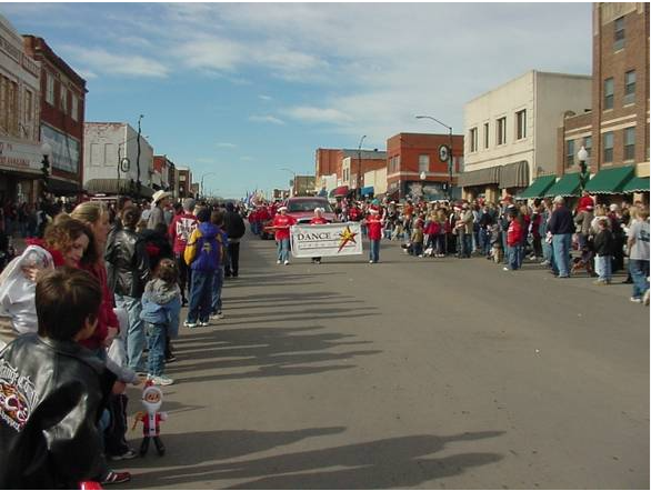 A parade filling a Cushing main street, with crowds along both sidewalks