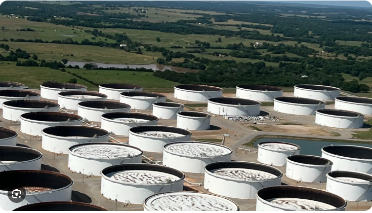 Aerial view of white crude-oil storage tanks surrounded by green prairie